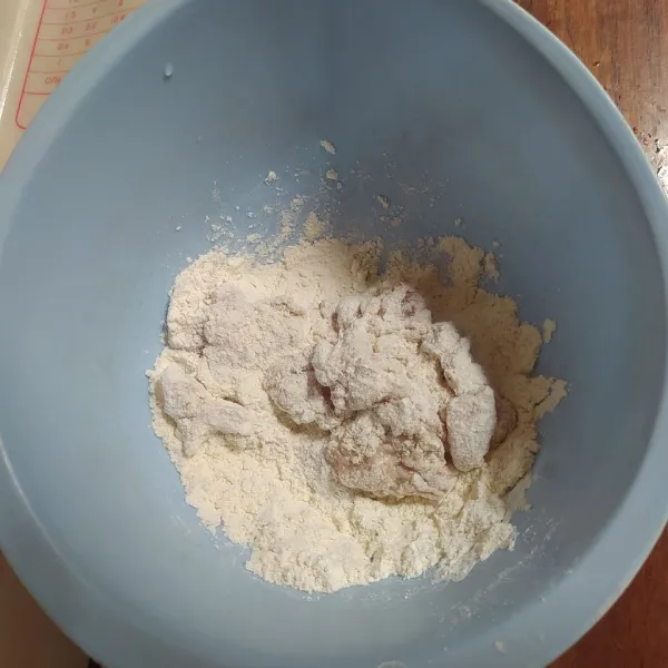 Masukkan ½ bagian ayam ke tepung kering, aduk-aduk sampai terbalut tepung kering.