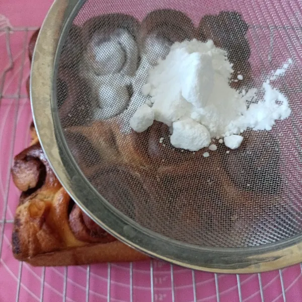 Setelah matang, keluarkan dari loyang, olesi dengan sedikit margarin lalu taburi dengan gula dingin donat.