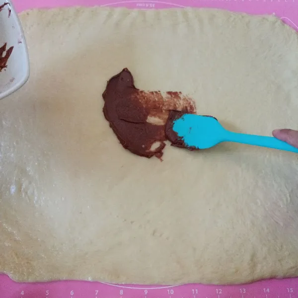 Olesi dengan campuran isian kayu manis hingga merata ke seluruh permukaan adonan. Resep cinnamon roll pada umumnya akan ditambahkan gula palem pada isiannya agar manis. Karena roti ini nantinya akan ditaburi dengan gula halus, maka isiannya tidak perlu ditambah gula palem.