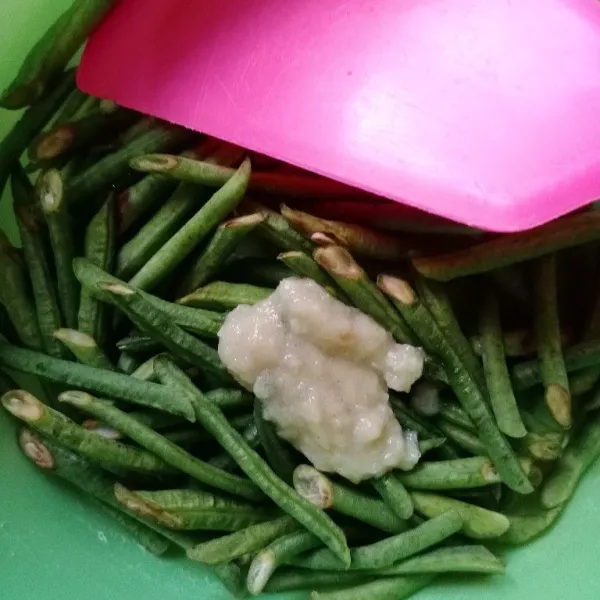 Masukkan bawang putih yang sudah digiling tadi ke kacang panjang dan aduk hingga rata.