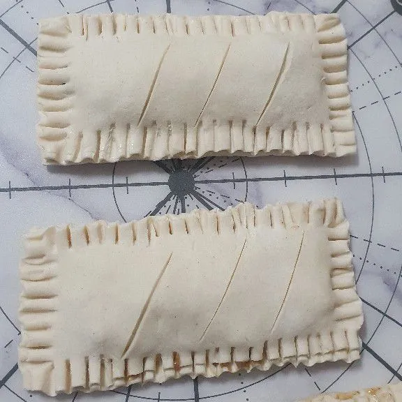 Tutup puff pastry yang sudah di isi dengan lapisan yang bersayat, lalu tekan-tekan dengan garpu bagian pinggiran puff pastry.
