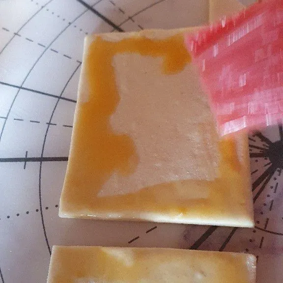 Olesi tiap ujung puff pastry bagian yang tak berlubang.