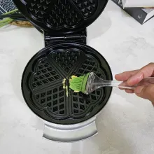 Oles cetakan waffle dengan margarin.