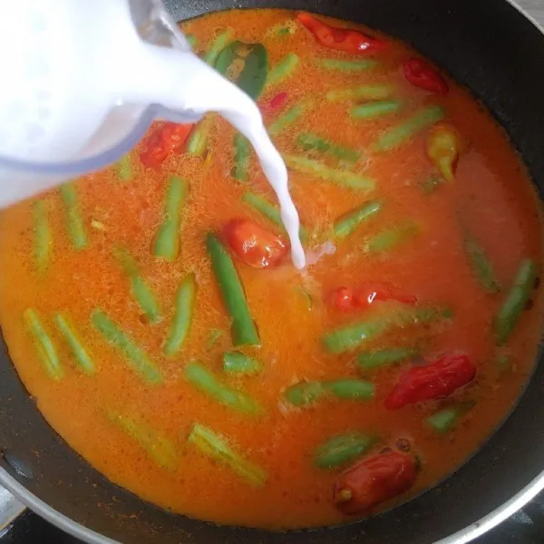 Kemudian tuang santan sambil diaduk agar santan tidak pecah, lalu masukan bumbu garam, kaldu bubuk dan gula, aduk rata.