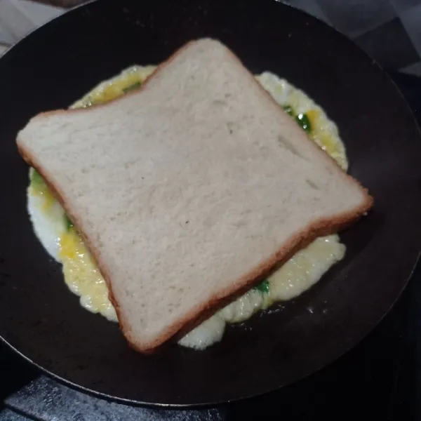 Taruh roti tawar diatas telur, rapikan sisinya.