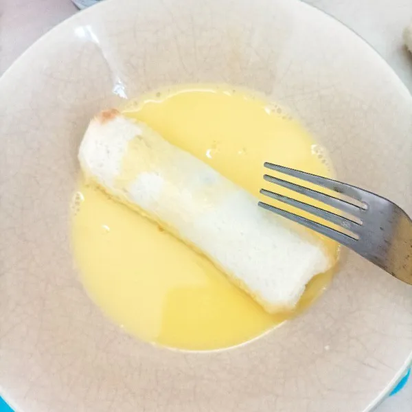Celupkan roti gulung dalam kocokan telur dan susu cair.