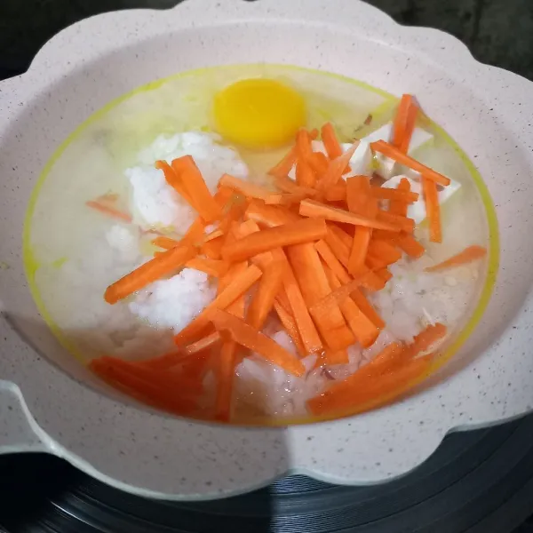 Masukkan nasi, wortel, tahu, telur, dan air.