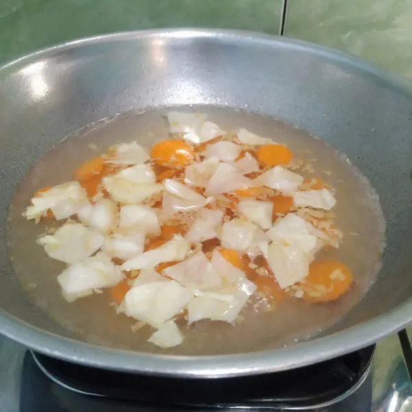 Tambahkan air lalu masak hingga mendidih. Masukkan wortel dan kol.