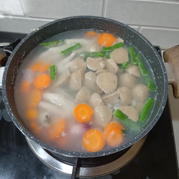 Tambahkan bakso, gula, garam dan kaldu bubuk. Masak sampai mekar.