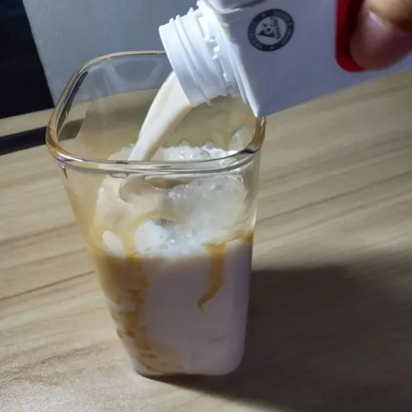 Masukan juga susu oat milk kedalam gelas yang berisi saus karamel dan es batu.