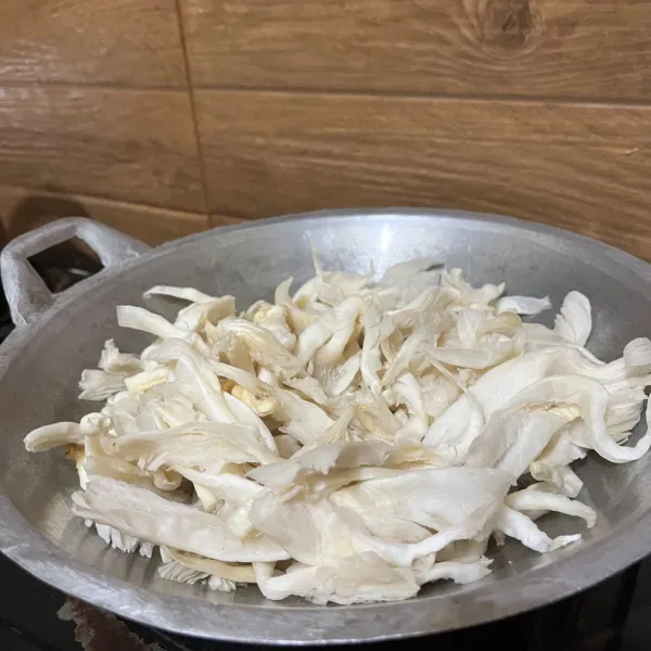Masukkan jamur tiram yang sudah dipotong kecil dan dicuci. Tambahkan air dan aduk hingga rata.