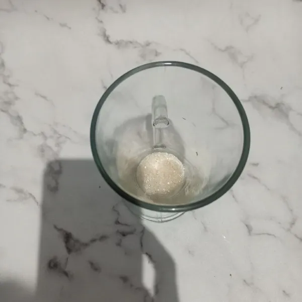 Masukkan gula pasir ke dalam gelas saji.