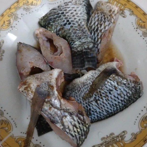 Taburi ikan dengan garam, penyedap rasa dan ketumbar bubuk, kemudian baluri seluruh sisi ikan agar merata, diamkan atau marinasi selama 15 menit.