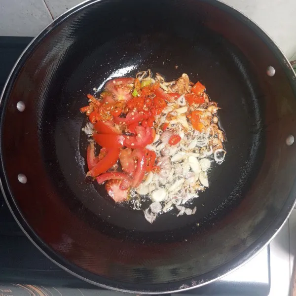 Tumis bawang merah dan bawang putih hingga harum, masukkan cabe rawit dan tomat. Aduk rata.