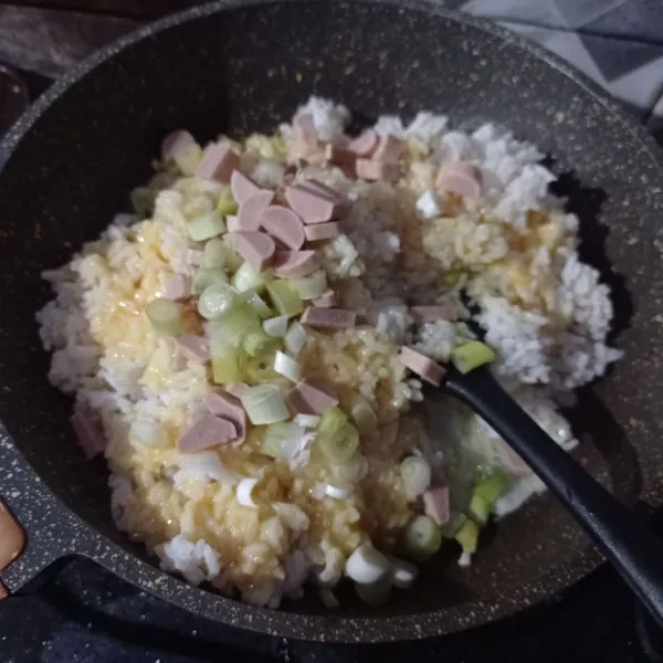 Masukan nasi, sosis, daun bawang, garam, pada, kaldu bubuk, kecap asin dan saus tiram, aduk sampai tercampur rata.
