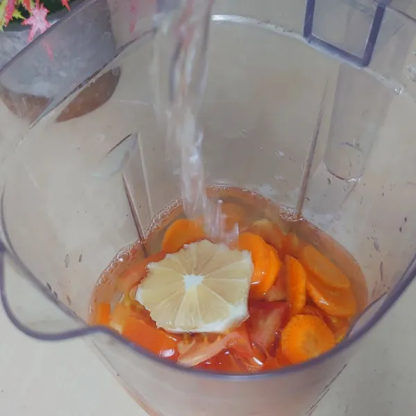 Masukkan wortel, tomat, lemon dan air ke dalam blender.