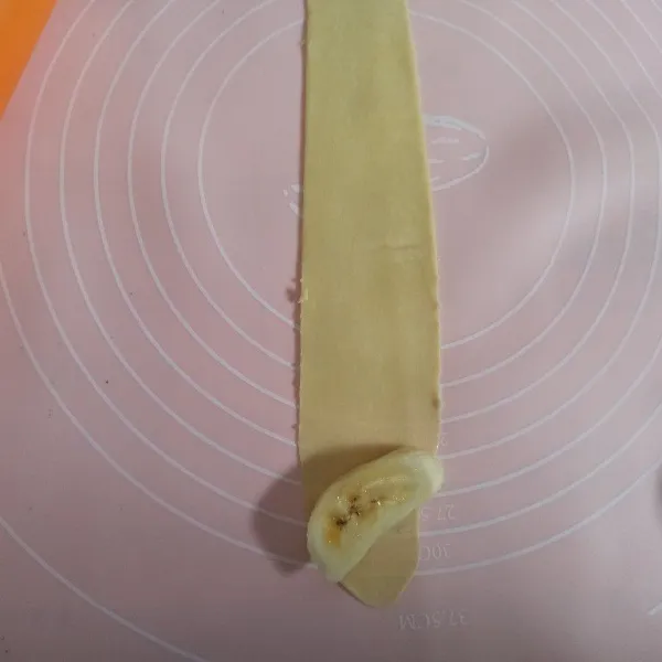 Gilas tipis dan memanjang adonan kulit kemudian tambahkan satu potong pisang, gulung dan cubit bagian ujungnya supaya saat digoreng tidak lepas.