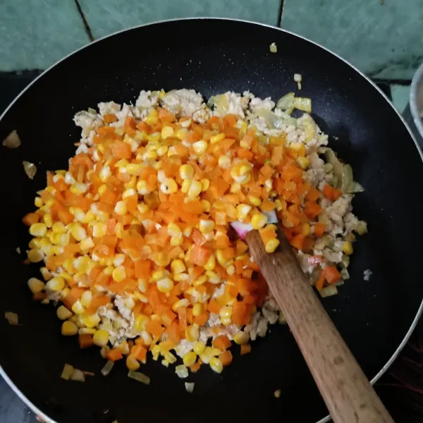 Setelah bawang bombay harum, masukkan ayam cincang, tumis hingga berubah warna, lalu masukkan sayuran wortel dan jagung setengah matang. Aduk hingga rata.