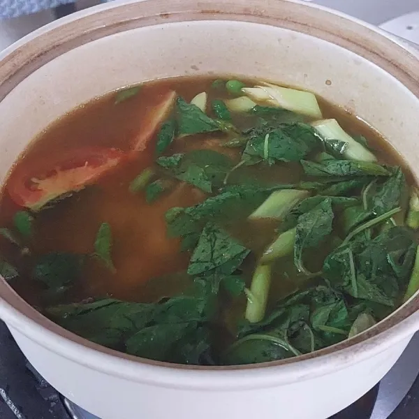 Tambahkankan air mendidih berikut sisa bumbu pelengkap, bumbu iris dan daun kemangi, masak sebentar dan sajikan.