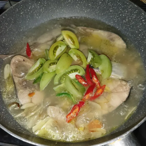 Tambahkan irisan tomat dan cabai, masak sampai ikan matang.