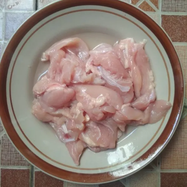 Potong memanjang daging ayam fillet kemudian cuci bersih dan tiriskan.