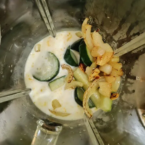 Masukkan rebusan zucchini, tumisan bawang putih dan bombay, tambahkan susu cair ke dalam blender dan haluskan