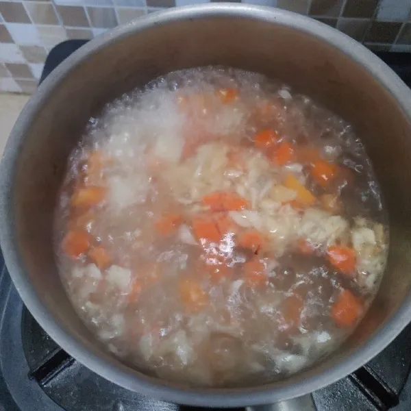 Didihkan air masukan kentang, wortel dan bawang putih yang sudah ditumis. Masak sampai mendidih dan sayuran matang.