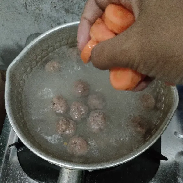 Rebus air sampai mendidih. Masukkan bola bola daging, masak sampai berubah warna. Masukkan wortel.