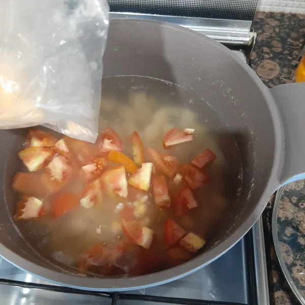 Masukan tomat dan jagung ke dalam rebusan singkong, tambahkan sisa air.