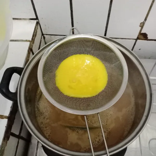 Setelah uap panas, masukkan telur dengan cara disaring. Aduk rata dan masak hingga mendidih.