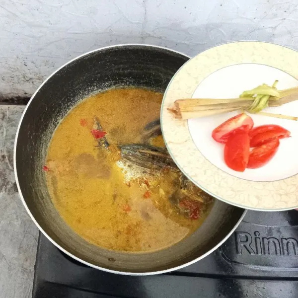 Masukkan serai yang sudah digeprek dan irisan tomat, lalu aduk kembali. Masak sampai air sedikit menyusut.