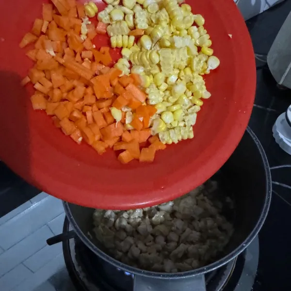 Masukkan potongan wortel dan jagung dan beri air.