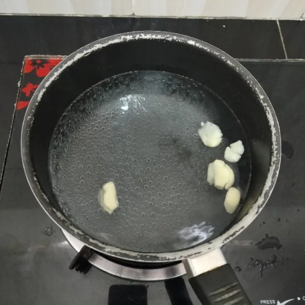 Rebus air dalam panci hingga hangat. Masukkan bawang putih. Masak hingga mendidih dan aromanya menguar.
