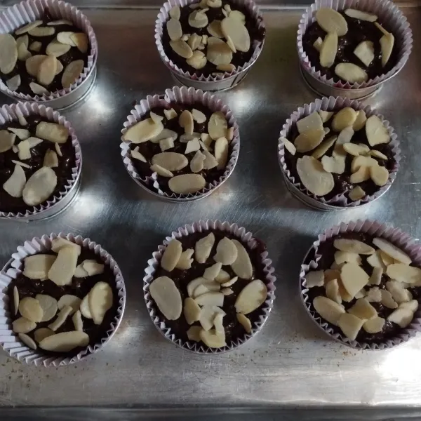 Masukkan adonan ke dalam loyang muffin, yang sudah di alas dengan cup kertas. Tuang 1/3 bagian. Lakukan sampai adonan habis, beri toping almond slice.