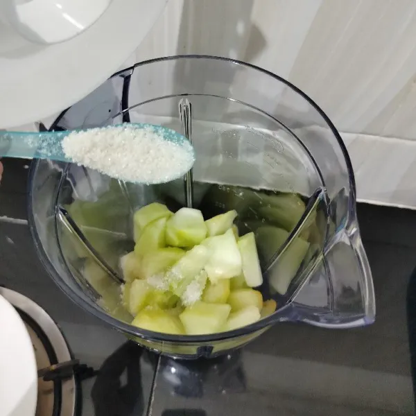 Masukkan melon ke dalam gelas blender, tambahkan gula pasir.