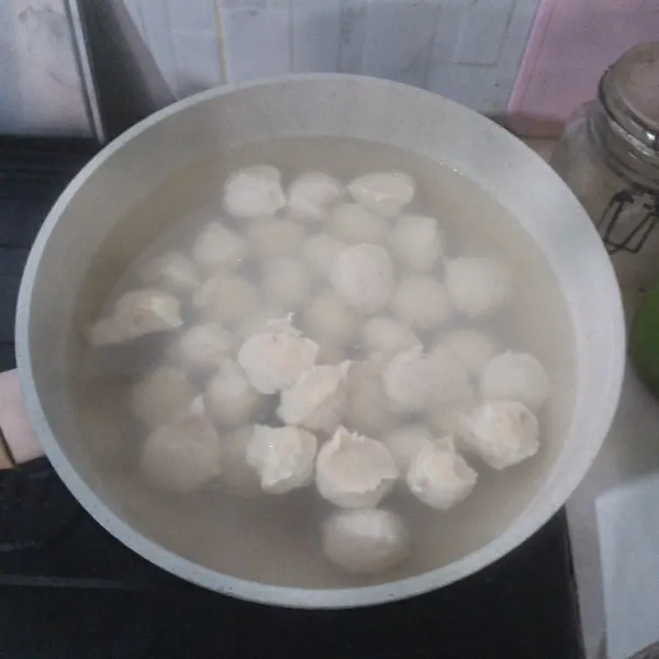 Bulatkan bakso ke dalam air mendidih, kecilkan api.