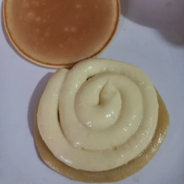 Ambil satu lembar pancake yang sudah matang, kemudian tambahkan isian custard dan tumpuk dengan lembaran lain. Siap disajikan.