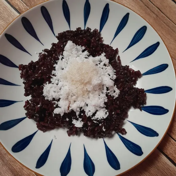 Tata ketan di piring beri taburan kelapa parut dan gula pasir.