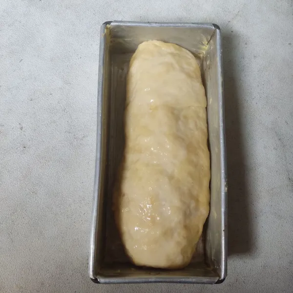Masukkan adonan ke loyang yang telah diolesi margarin. Biarkan hingga mengembang lalu olesi permukaan adonan dengan air.