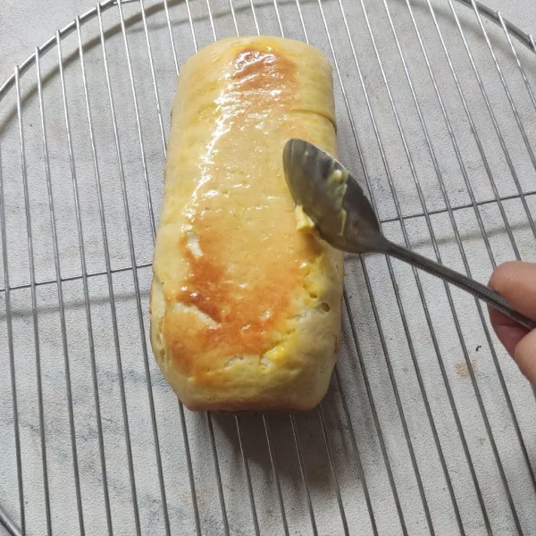 Setelah roti tawar matang lalu keluarkan dari loyang dan beri olesan margarin di permukaannya agar tampilan permukaan roti tawar bisa terlihat cantik.