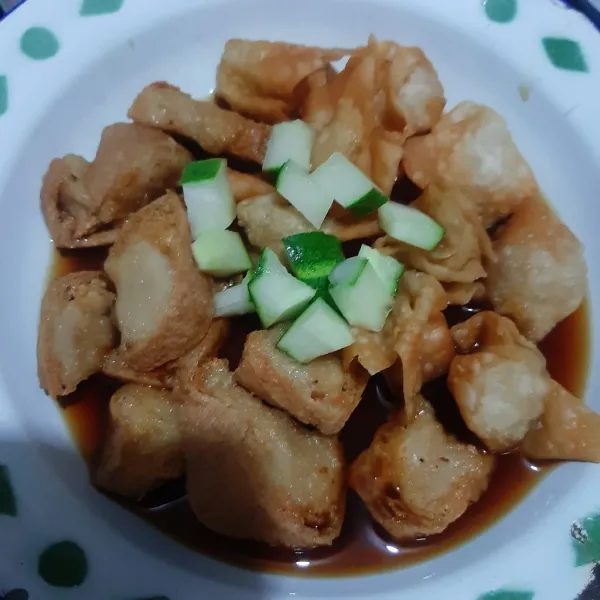 Tata tahu bakso, pangsit goreng di piring. Beri kuah rujak dan timun.