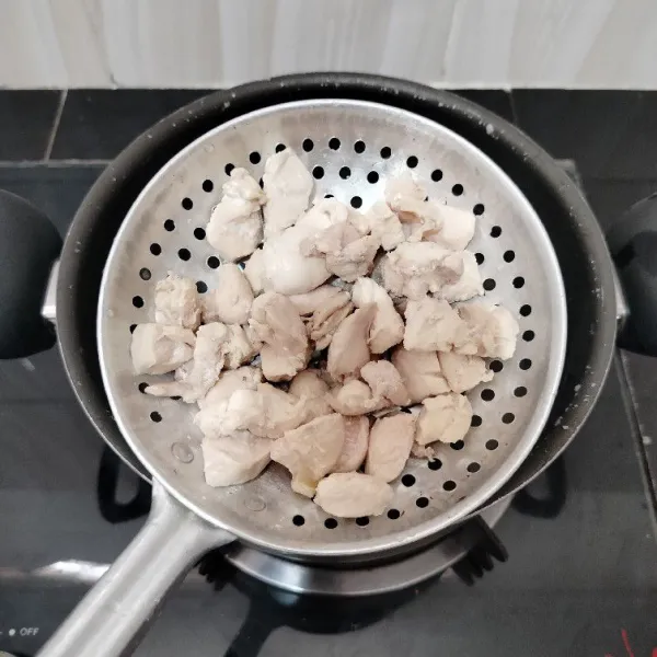 Potong dadu fillet dada ayam, lalu rebus sebentar dalam air mendidih. Tiriskan ayam, dan buang air rebusannya.