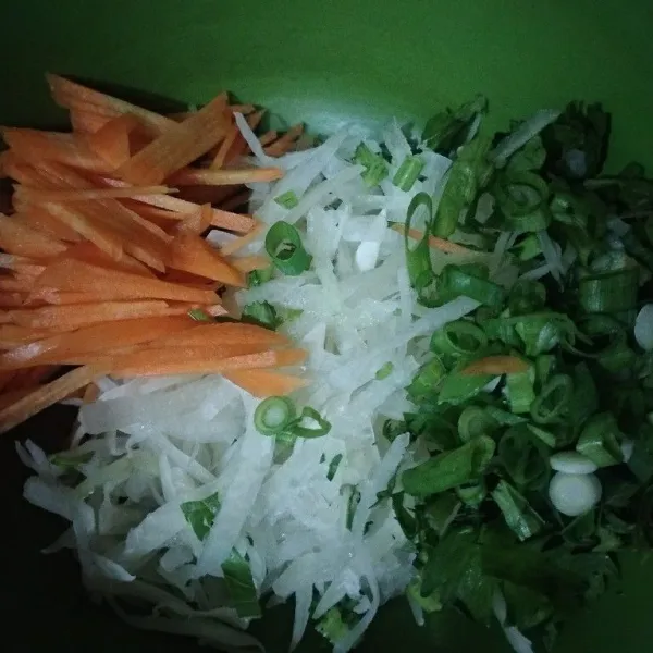 Serut pepaya muda, potong korek wortel dan iris tipis-tipis daun bawang dan seledri. Cuci lalu masukkan ke dalam wadah.