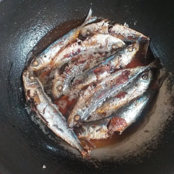 Panaskan minyak masukan ikan pindang lalu ditutup masak hingga setengah mateng matikan kompor tunggu sebentar baru dibuka tutupnya .