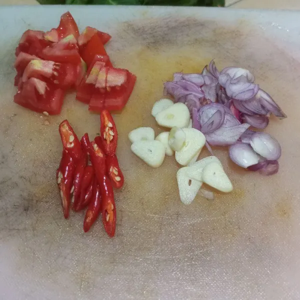 Siapkan talenan, Iris-iris bawang merah, bawang putih, cabe serta tomat.