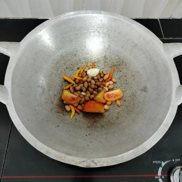 Goreng kacang tanah, bawang putih, cabe rawit, dan tomat hingga matang.