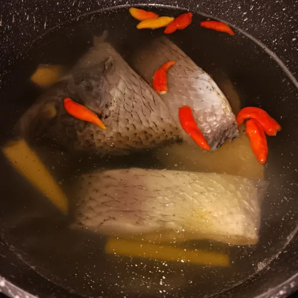 Setelah mendidih kecilkan api, masukkan ikan, cabe rawit, garam dan kecap ikan. Masak selama 20 menit dalam keadaan panci tertutup.