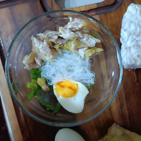 Tata bahan pelengkap di mangkuk seperti telur bihun daun bawang dan ayam suwir. Tuang kuah soto.