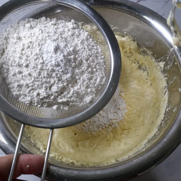 Tambahkan tepung terigu dan baking powder sambil diayak.