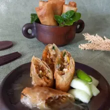 Lumpia isi sayuran siap disajikan bersama saus dan potongan mentimun.
